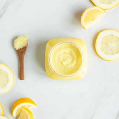 Open jar of Citrus Bliss Body Polish with fresh lemon slices