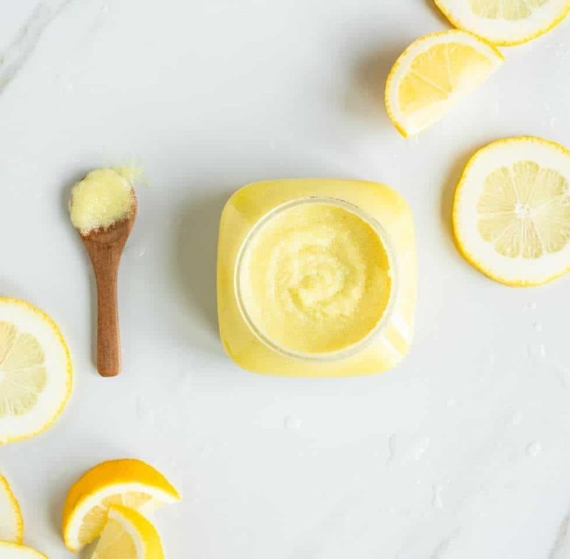Open jar of Citrus Bliss Body Polish with fresh lemon slices
