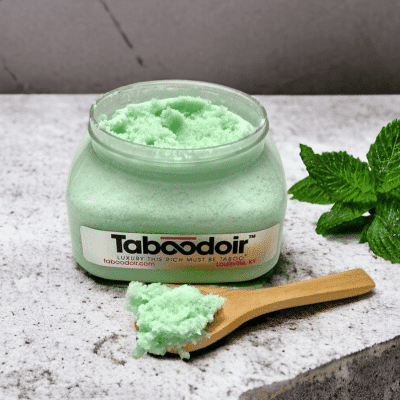 Open jar of Taboodoir Mint to Tease Body Polish with a wooden spoon and fresh mint leaves